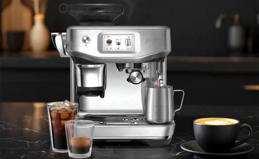 Silver espresso machine on a dark countertop with coffee and drinks.